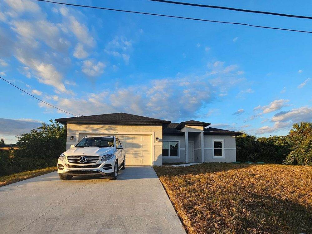 Single-family ranch home with a driveway and white SUV at dusk, represented by Dgani Group in South Florida