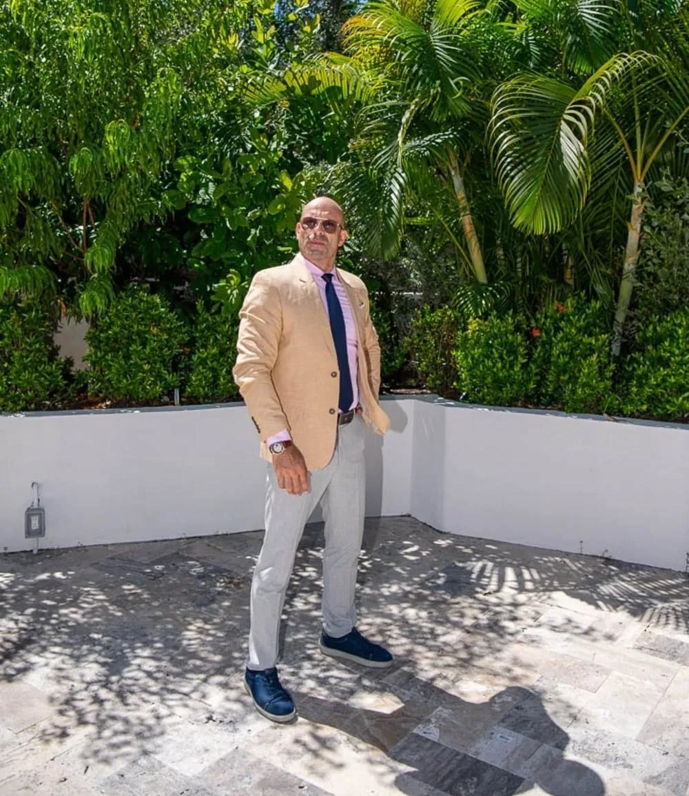 Shalom Dgani, founder of Dgani Group, standing outdoors at a South Florida property with tropical landscaping