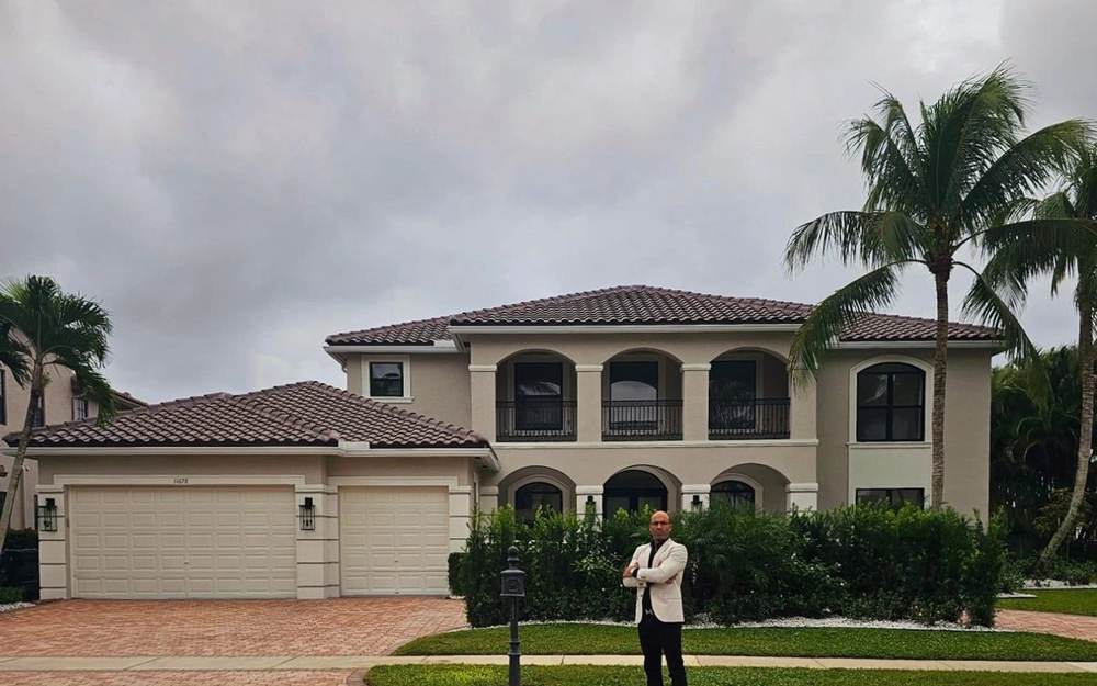 Two-story estate home with arched windows and palm trees, represented by Dgani Group in South Florida