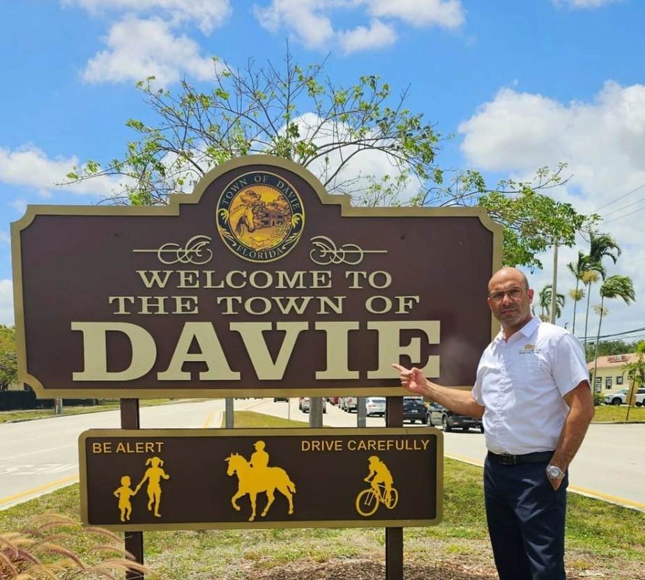 Shalom Dgani standing next to the Welcome to the Town of Davie sign, Davie FL